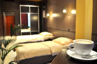 a cup of coffee sitting on a table with two beds at Hotel Fortuna in Banja Luka