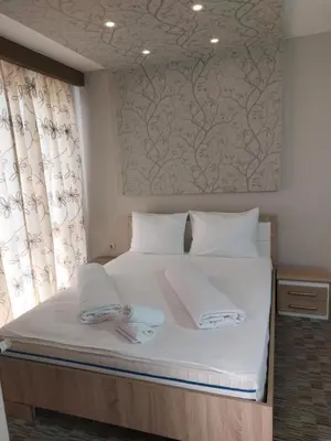 a bedroom with a bed with white sheets and a window at Motel Bajra in Travnik
