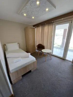 a bedroom with two beds and a table and a window at Motel Bajra in Travnik