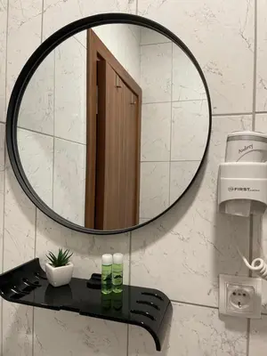 a mirror on a bathroom wall with a black shelf at Apartmani Brko in Kotor-Varoš