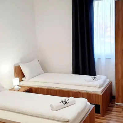 a room with two beds and a window at Apartmani Brko in Kotor-Varoš