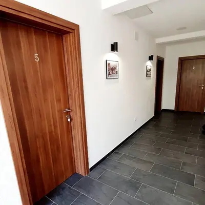 a hallway with a wooden door and a tile floor at Apartmani Brko in Kotor-Varoš
