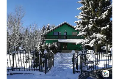 a green house with a gate in the snow at Holiday home Veky in Kupres