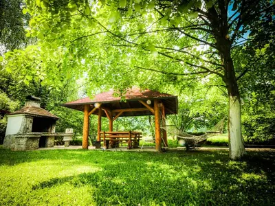 a wooden gazebo with a picnic table in a park at Home Eden Dobrenica in Bihać