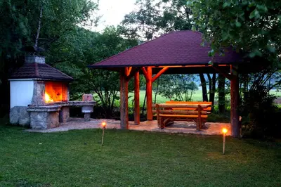 a wooden bench and a gazebo with candles in the grass at Home Eden Dobrenica in Bihać