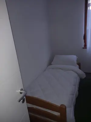 a small bedroom with a bed in a white room at Apartman Tea in Kupres