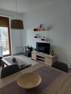 a living room with a flat screen tv and a table at Apartman Tea in Kupres