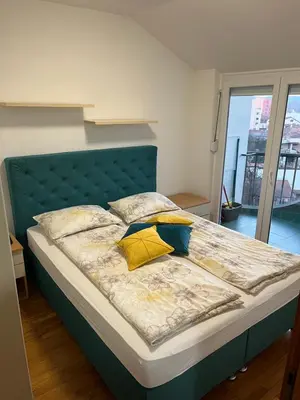 a bed with a green headboard and two yellow pillows at Lara in Banja Luka