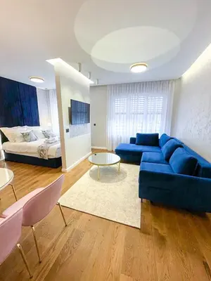 a living room with a blue couch and a bed at Premium Apartmani Banja Luka in Banja Luka