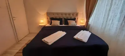 a bedroom with a large bed with two towels on it at Lux Apartment ll Prijedor in Prijedor