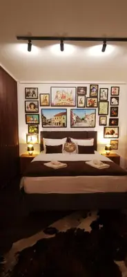 a bedroom with a large bed with pictures on the wall at Tuzla Trg - Tuzla Square in Tuzla