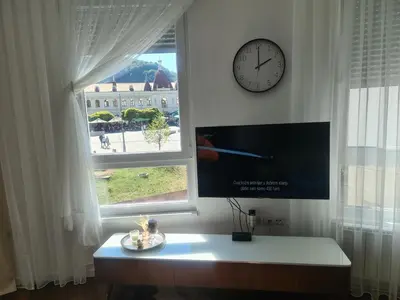 a clock on a wall next to a window at Tuzla Trg - Tuzla Square in Tuzla