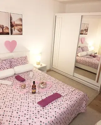 a bedroom with a pink bed with a bottle of wine at Apartman Dunja in Prijedor
