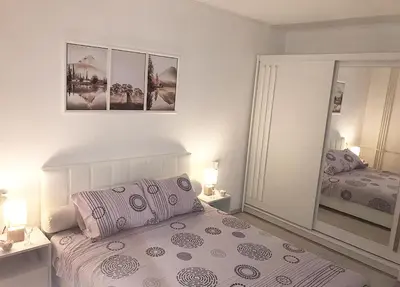 a white bedroom with a bed and a mirror at Apartman Dunja in Prijedor