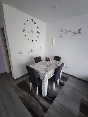 a dining room table with chairs and a clock on the wall at Stan na dan Apartman KRISFIL Prnjavor in Prnjavor