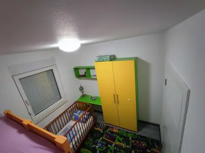 a bedroom with a crib and a yellow cabinet at Stan na dan Apartman KRISFIL Prnjavor in Prnjavor