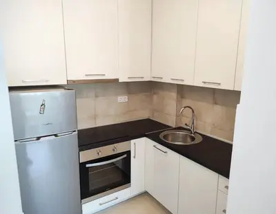a kitchen with white cabinets and a stainless steel refrigerator at S&S Apartman Banja Luka in Banja Luka