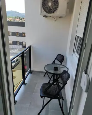 a balcony with two chairs and a table and a fan at S&S Apartman Banja Luka in Banja Luka