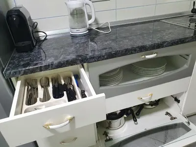 a kitchen counter with white drawers and plates at Stan u centru Prnjavor in Prnjavor