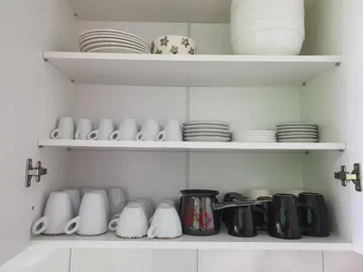 a cupboard filled with white and black cups and plates at Stan u centru Prnjavor in Prnjavor