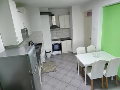 a kitchen with a table and chairs and a refrigerator at Stan u centru Prnjavor in Prnjavor
