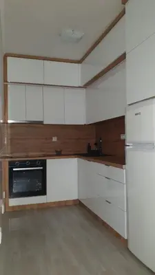 an empty kitchen with white cabinets and a refrigerator at Apartman Basic 2 in Doboj