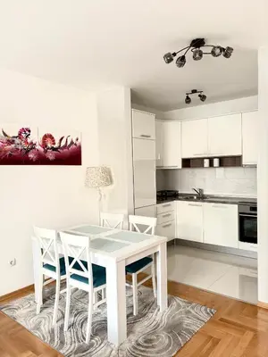a white kitchen with a white table and chairs at Iskra in Banja Luka
