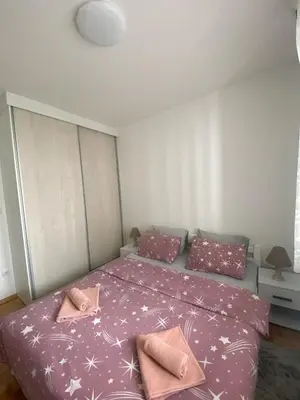 a bedroom with a bed with pink sheets and pillows at Iskra in Banja Luka