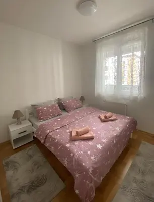 a bedroom with two beds with pink sheets and a window at Iskra in Banja Luka
