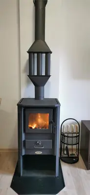 a black stove with a fire in a room at Apartman ALTA in Vlasic