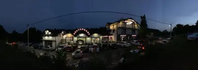 a building with cars parked in a parking lot at night at MOTEL ALADIN in Cazin