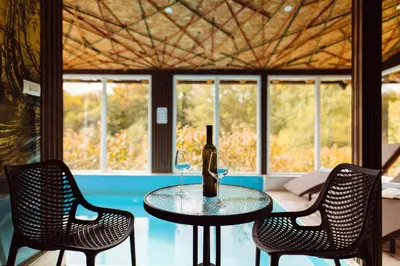 a table with a bottle of wine and two chairs at Srce Kozare in Prijedor