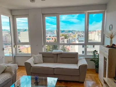 a living room with a couch and large windows at Stan na dan Bella in Banja Luka
