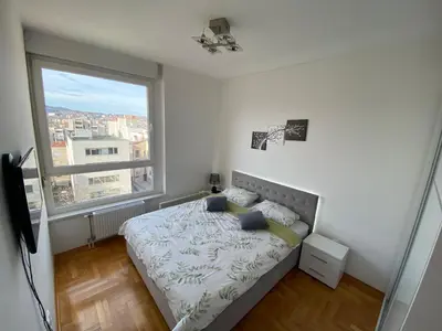 a bedroom with a bed and a large window at Stan na dan Bella in Banja Luka