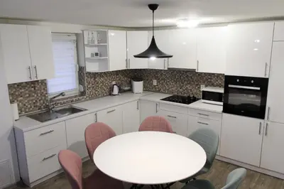 a white kitchen with a white table and chairs at Villa Noa Kupres in Kupres