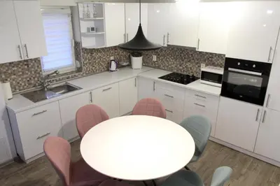 a white kitchen with a white table and chairs at Villa Noa Kupres in Kupres