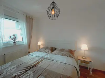 a bedroom with a bed and a window and a chandelier at Orhidea Doboj in Doboj