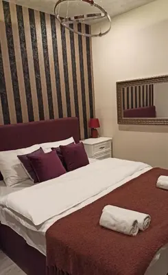 a bedroom with a large white bed with purple pillows at Apartmani President IV in Banja Luka
