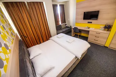 a hotel room with a bed and a desk and a television at Zlatna Kruna in Banja Luka