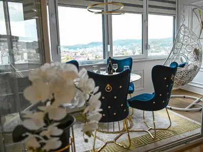 a dining room with a table and chairs and windows at Luxury Apartment Karic FREE parking in Tuzla