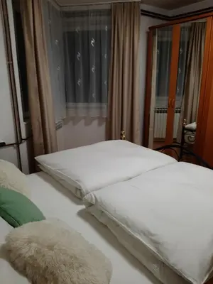 a bedroom with a bed with white sheets and a window at Apartman Hana in Sanski most