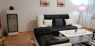 a living room with a black leather couch and a table at Apartman Hana in Sanski most