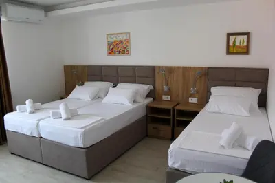 two beds in a hotel room with white sheets at Royal Apartmani in Banja Luka