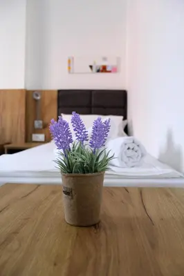 a vase with purple flowers sitting on the floor next to a bed at Royal Apartmani in Banja Luka