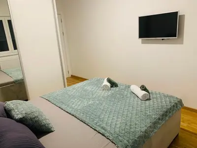a bedroom with a bed with a tv on the wall at Apartman LUAN in Banja Luka