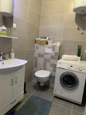 a bathroom with a toilet and a washing machine at Apartman LUAN in Banja Luka