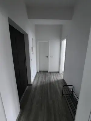 an empty hallway with a black door and wooden floors at Apartman San in Bugojno