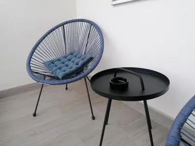 a blue chair and a table next to a wall at Apartman Merkator in Banja Luka