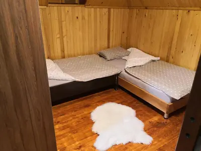 a room with two beds and a white rug at Vikendica Ajla in Travnik