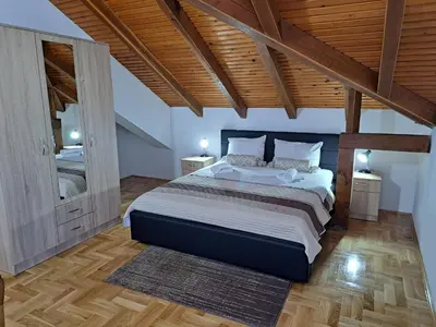 a bedroom with a large bed and wooden ceilings at Apartman Bubic in Banja Vrućica